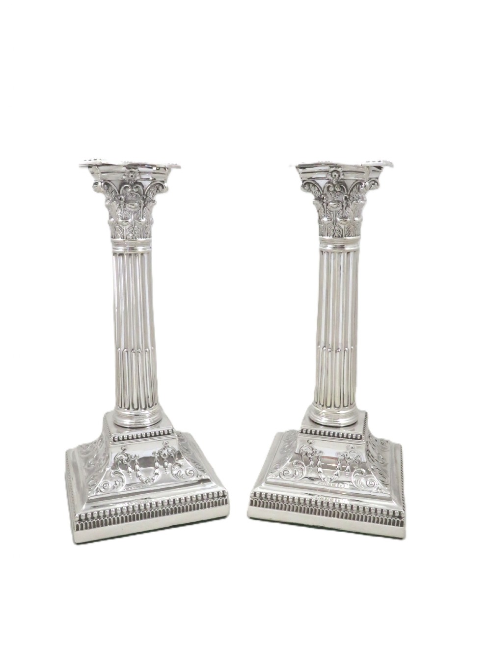 A pair of antique sterling silver candlesticks featuring fluted Corinthian columns on square decorated stepped bases. View VI