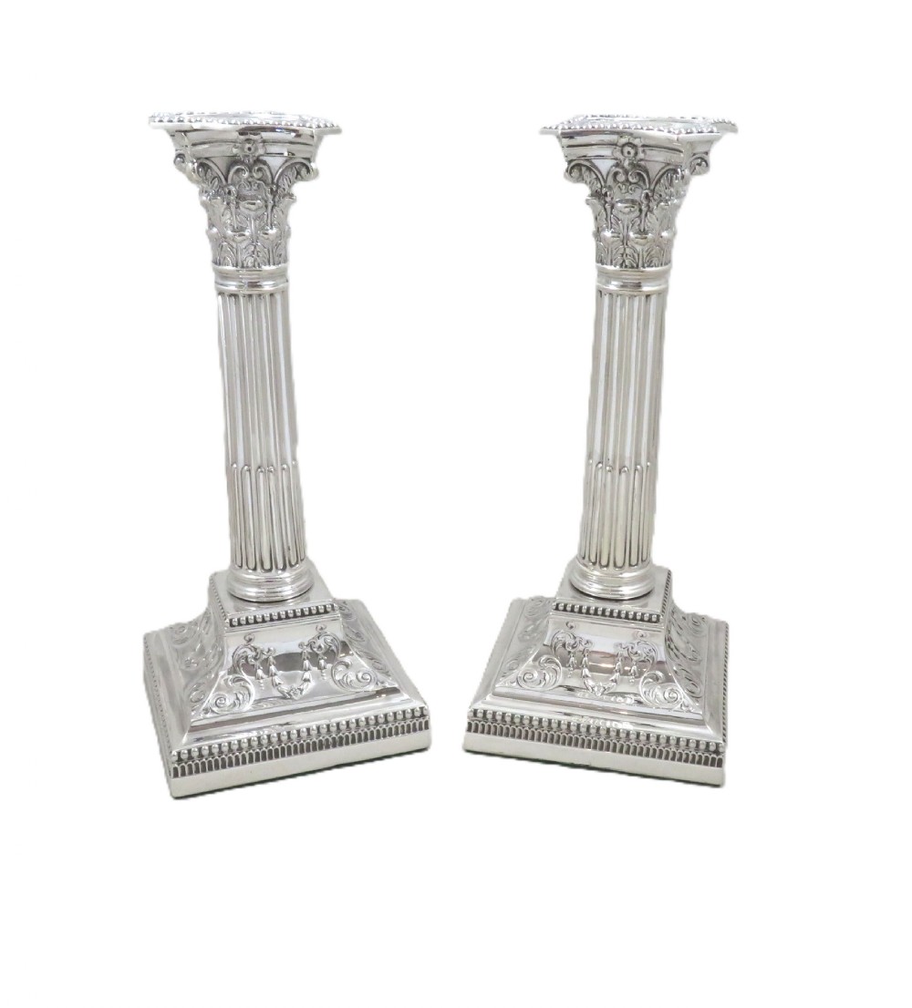 A pair of antique sterling silver candlesticks featuring fluted Corinthian columns on square decorated stepped bases. View VIII