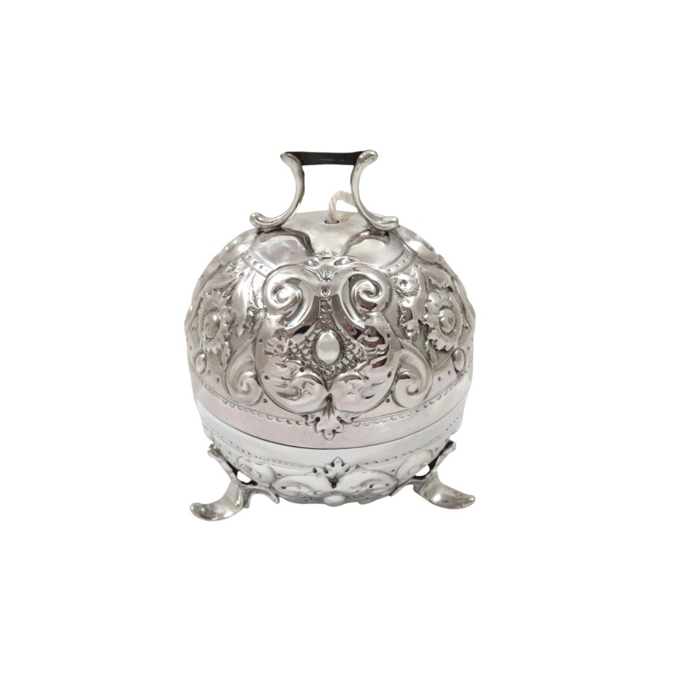 A spherical Victorian sterling silver string box with elaborate repousse scroll ornamentation, resting on three scroll feet.