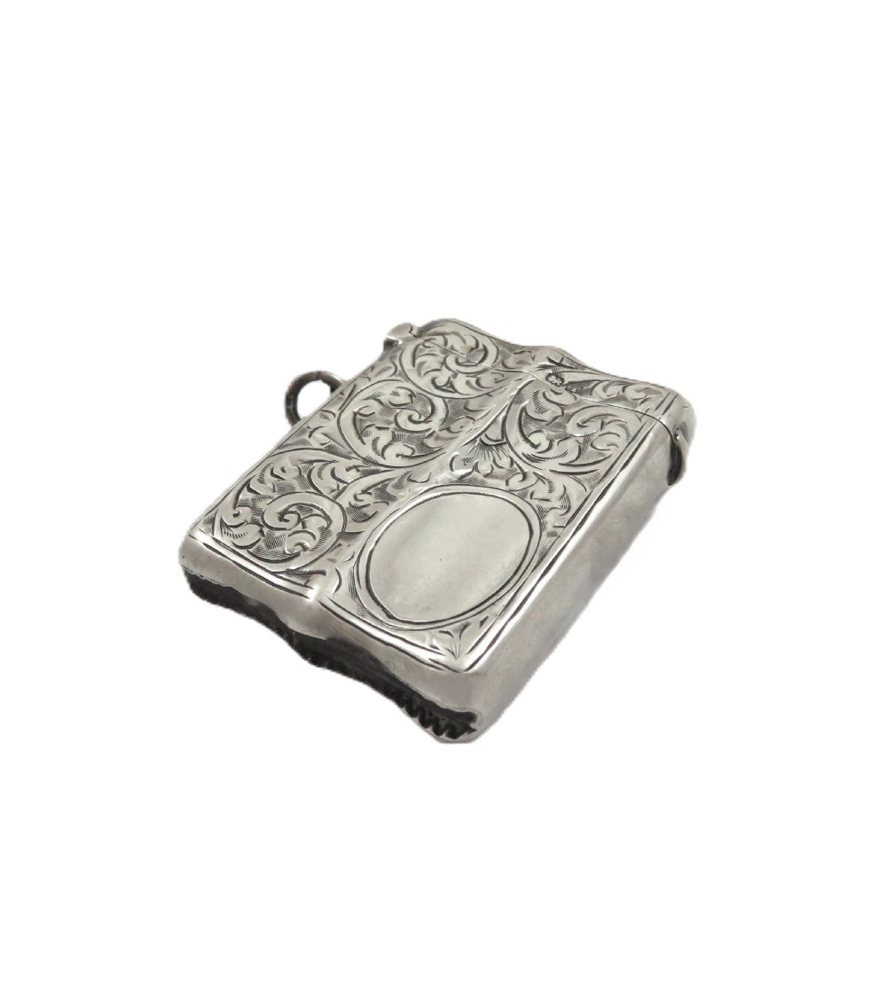 A shaped sterling silver vesta case featuring detailed scrollwork floral engraving, a vacant oval cartouche, and a side suspension ring. View VII