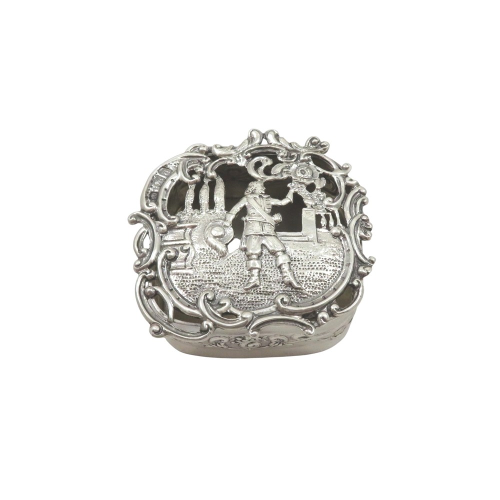 A small late Victorian sterling silver box featuring intricate pierced scrollwork and a central embossed scene depicting a figure in historic dress.