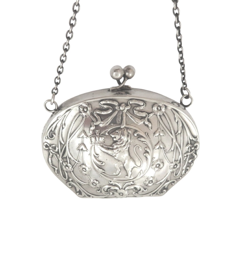 An Edwardian sterling silver chain purse with a kiss-lock clasp, embossed with floral swags, ribbons, and a central medallion depicting a rampant lion.