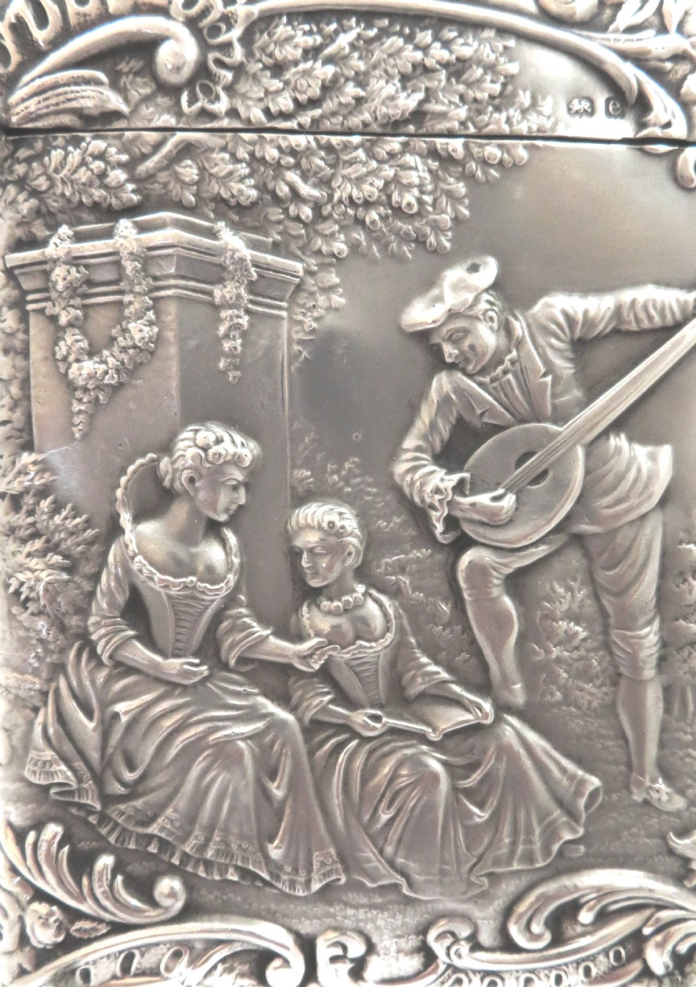 An Edwardian sterling silver card case featuring an embossed relief scene of figures playing music outdoors. View VI