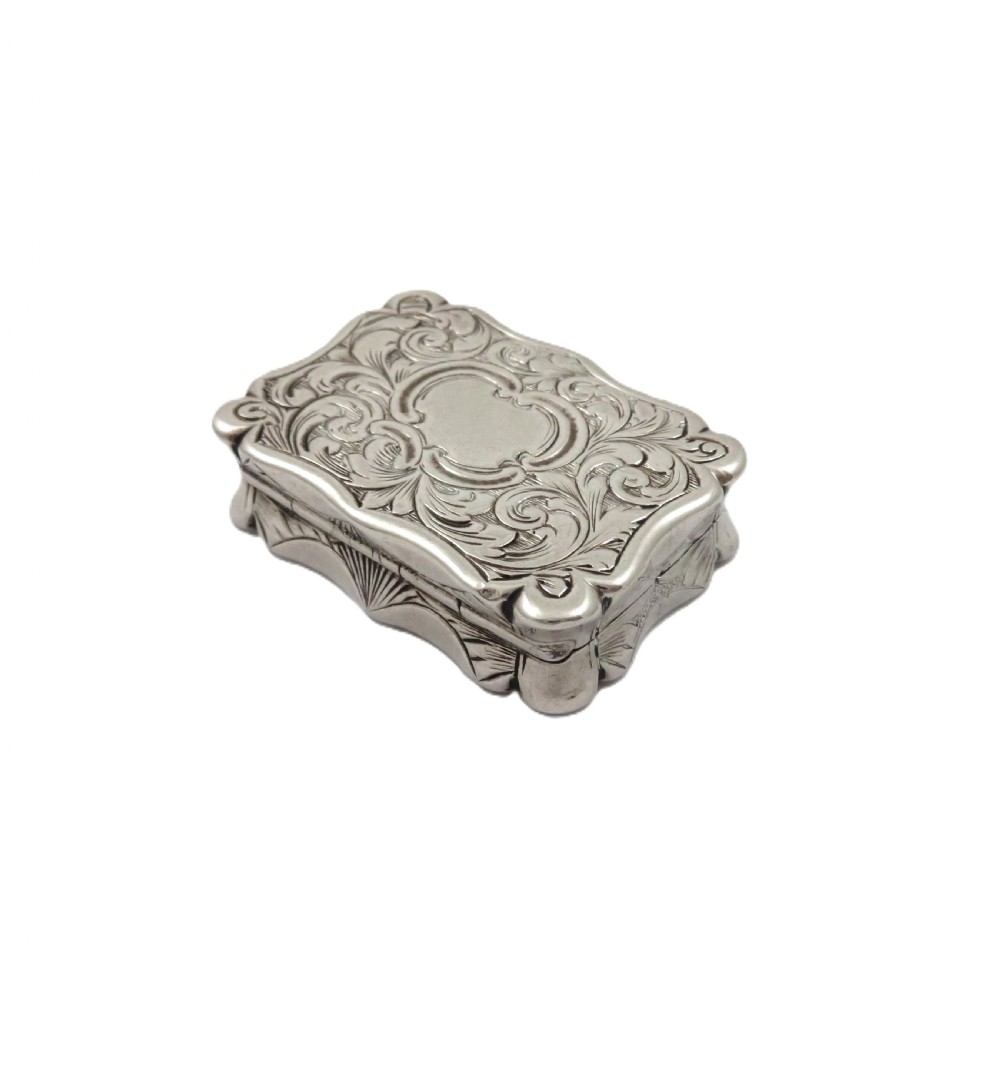 A small rectangular Victorian sterling silver vinaigrette box featuring intricate foliate engraving and a serpentine outline.