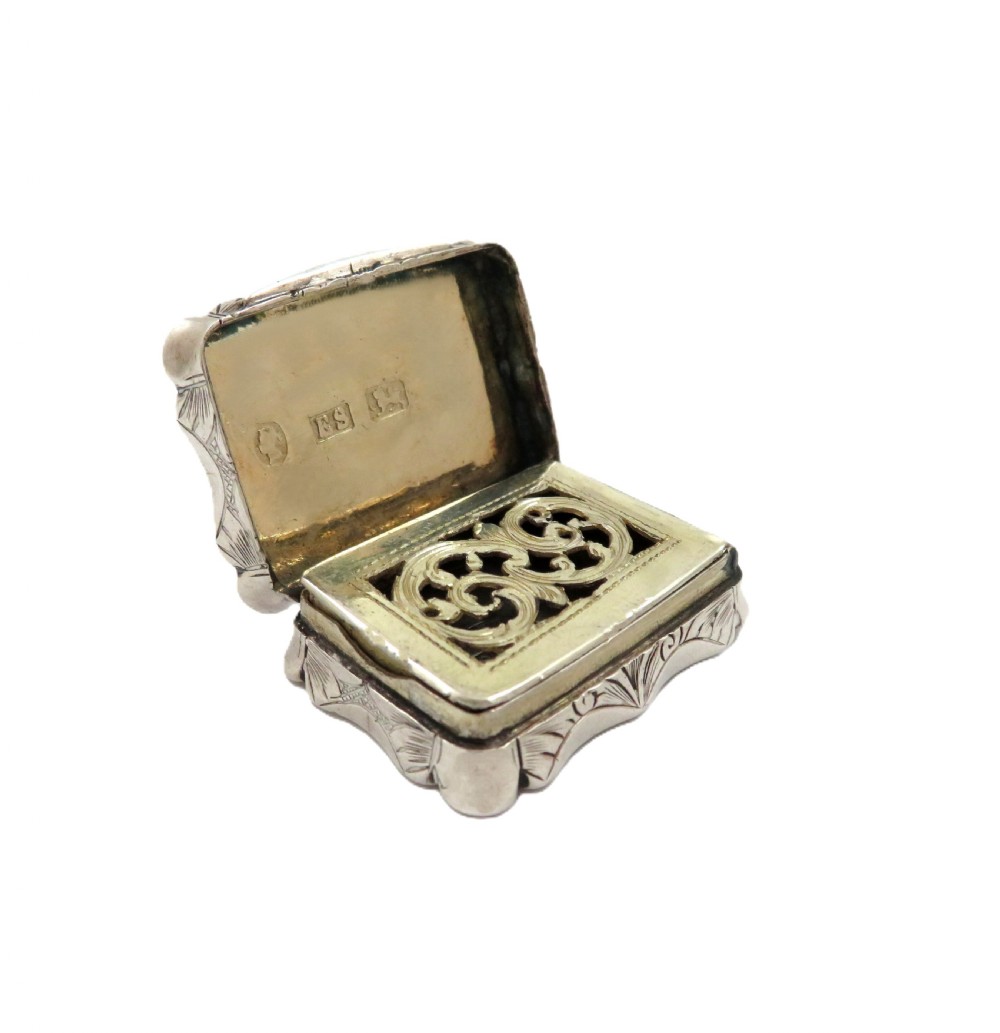 A small rectangular Victorian sterling silver vinaigrette box featuring intricate foliate engraving and a serpentine outline. View II