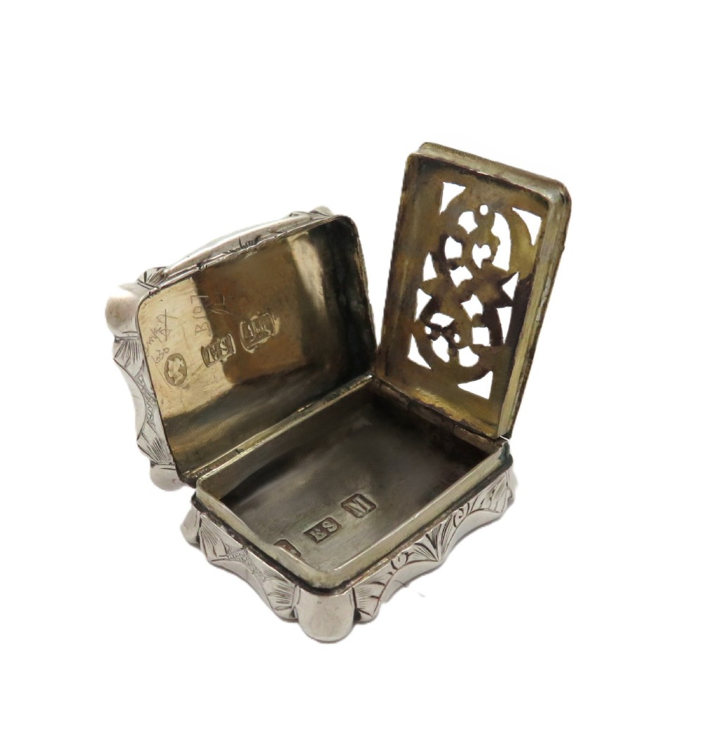 A small rectangular Victorian sterling silver vinaigrette box featuring intricate foliate engraving and a serpentine outline. View V