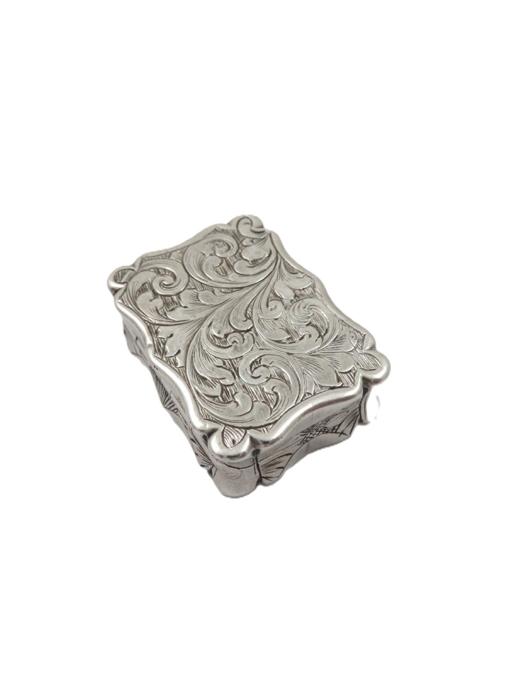 A small rectangular Victorian sterling silver vinaigrette box featuring intricate foliate engraving and a serpentine outline. View VII