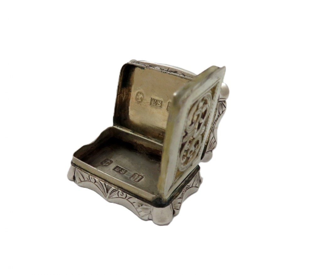 A small rectangular Victorian sterling silver vinaigrette box featuring intricate foliate engraving and a serpentine outline. View IX
