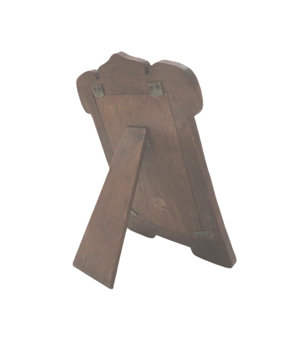 An Art Nouveau sterling silver photo frame with fluid curves mounted on a dark wooden backing. View VI