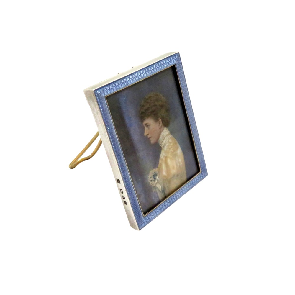 An antique sterling silver easel picture frame featuring a light blue guilloche enamel border framing a portrait of a woman.