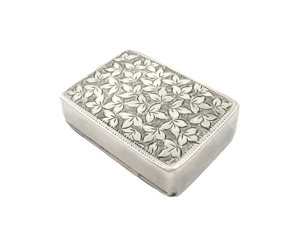 A small rectangular Victorian sterling silver box featuring relief foliage motifs and an unengraved central cartouche. View VI