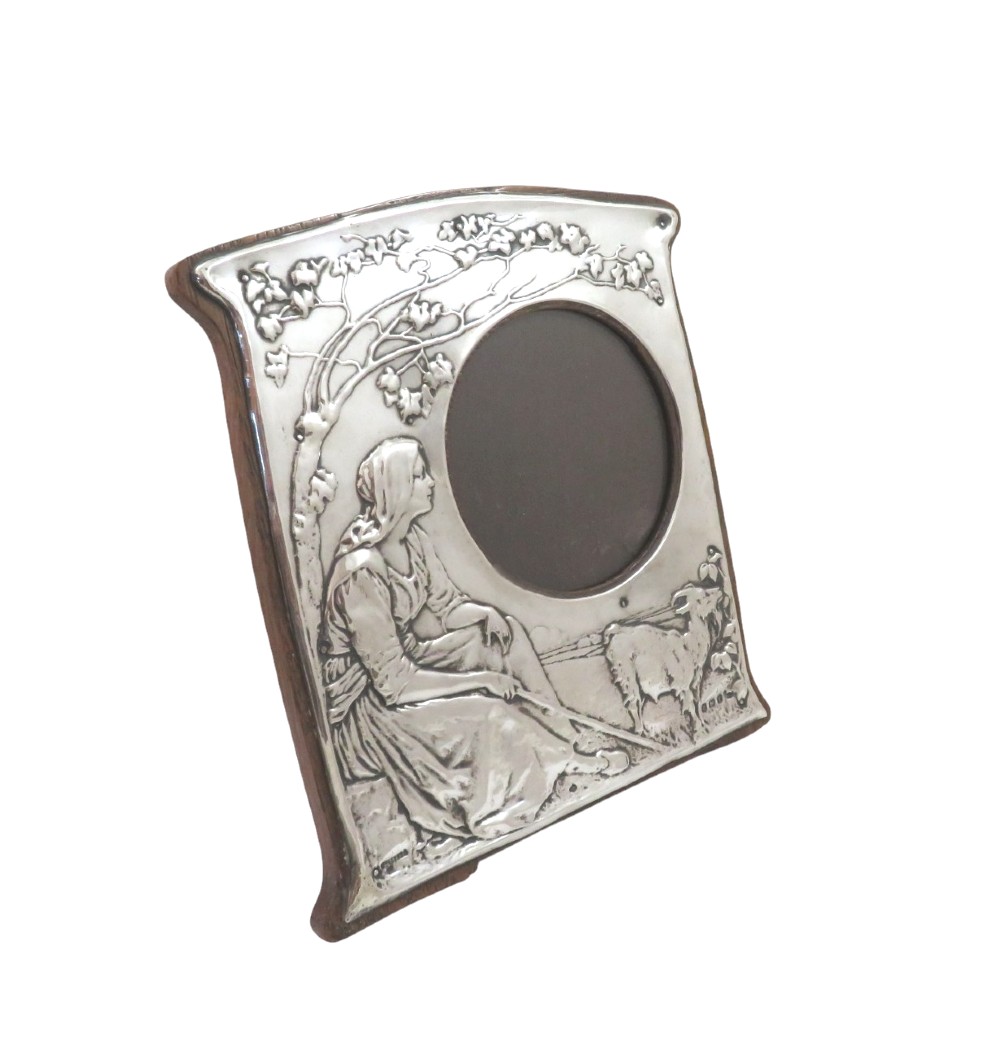 An Art Nouveau sterling silver photo frame featuring an embossed scene of a seated girl beneath a tree with a goat beside a circular opening. View VIII