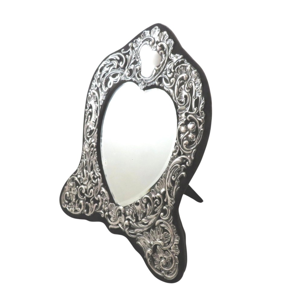 An Edwardian sterling silver dressing table mirror featuring elaborate repousse scrollwork detailing and an easel backing. View VIII