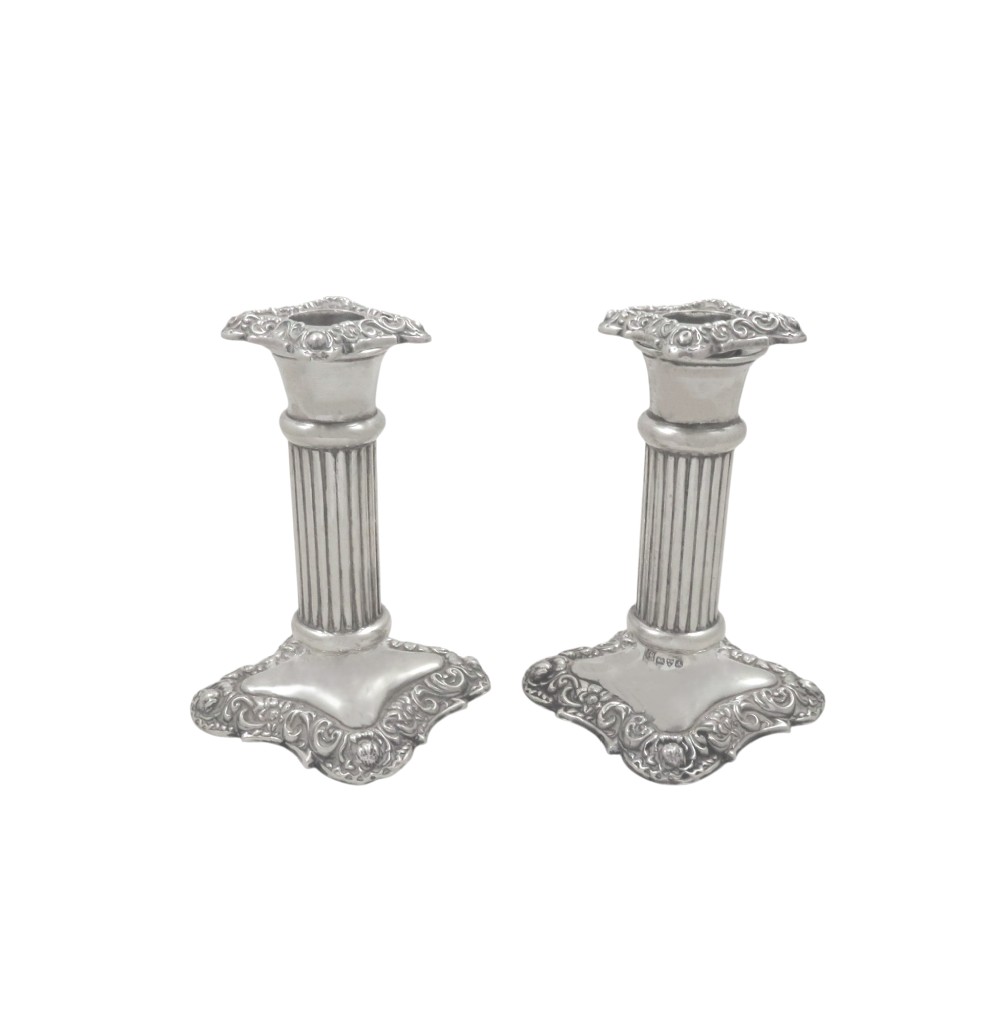 A pair of Edwardian sterling silver candlesticks featuring fluted columns and embossed ornate scrollwork bases. View VI