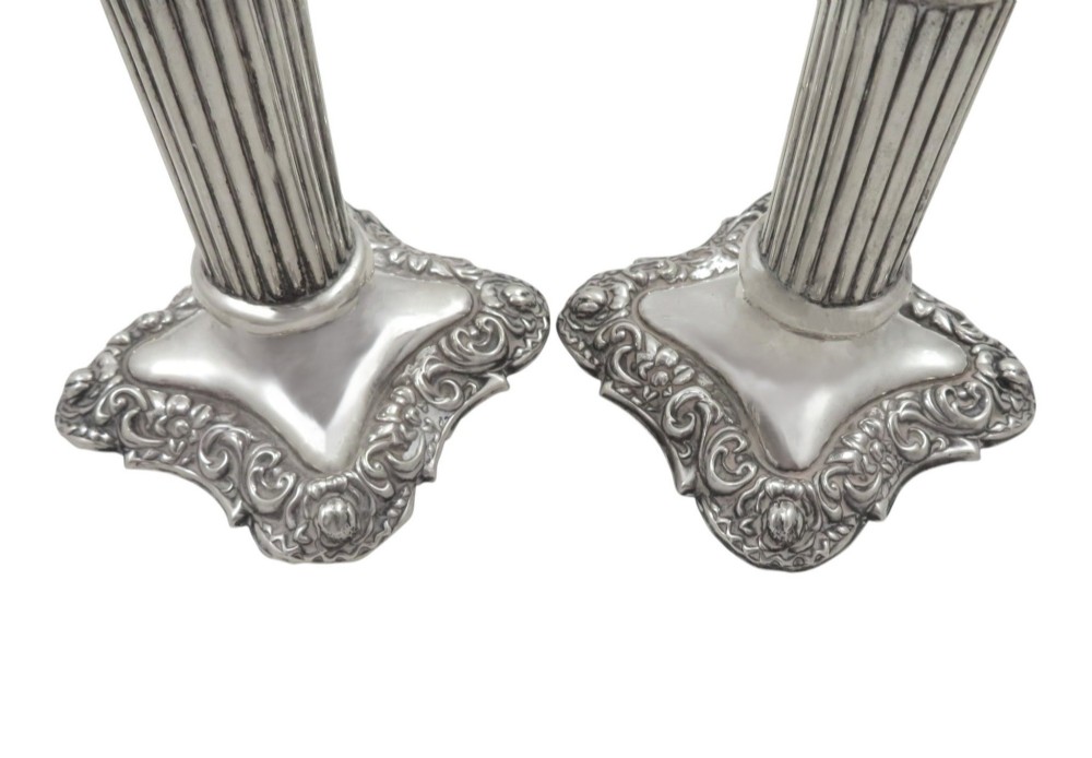 A pair of Edwardian sterling silver candlesticks featuring fluted columns and embossed ornate scrollwork bases. View VII