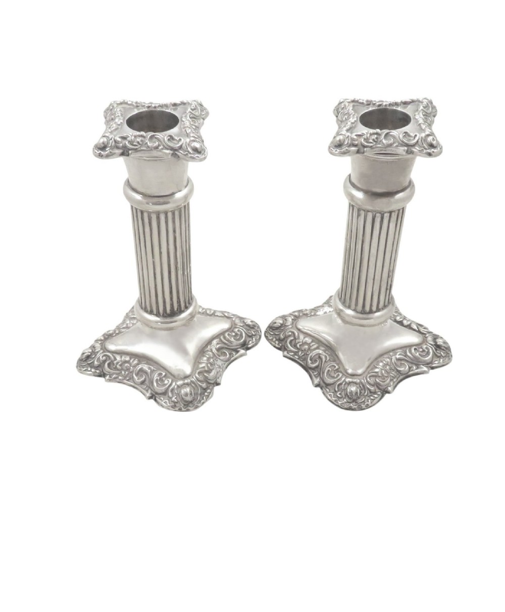 A pair of Edwardian sterling silver candlesticks featuring fluted columns and embossed ornate scrollwork bases. View VIII
