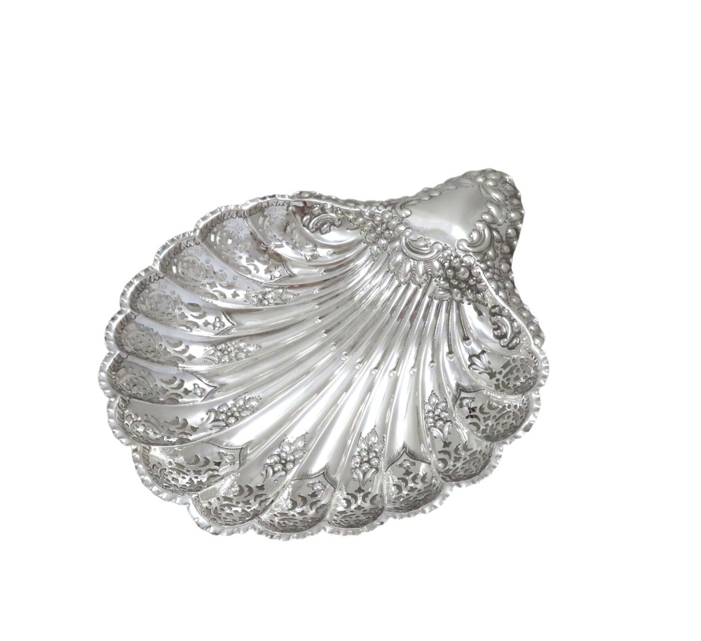 A Victorian sterling silver dish shaped like a scallop shell with intricate repousse foliage and pierced fluted details. View VIII