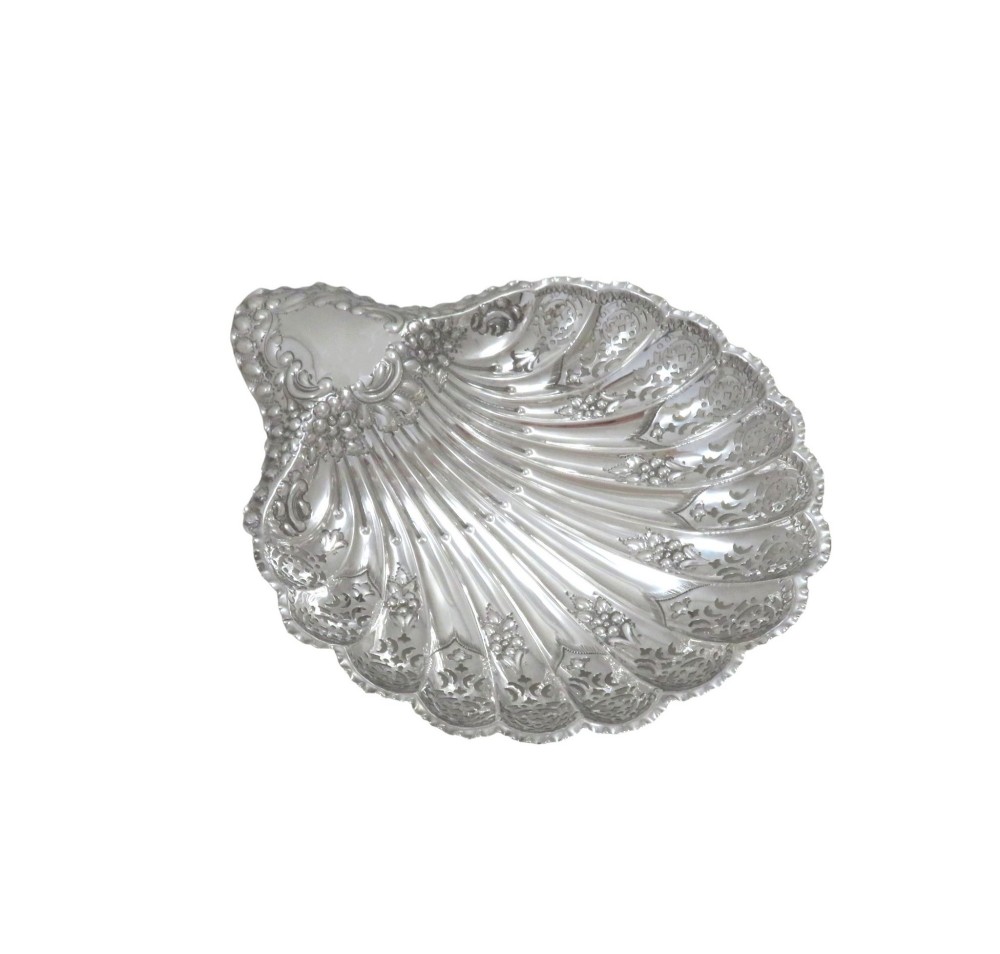 A Victorian sterling silver dish shaped like a scallop shell with intricate repousse foliage and pierced fluted details. View X