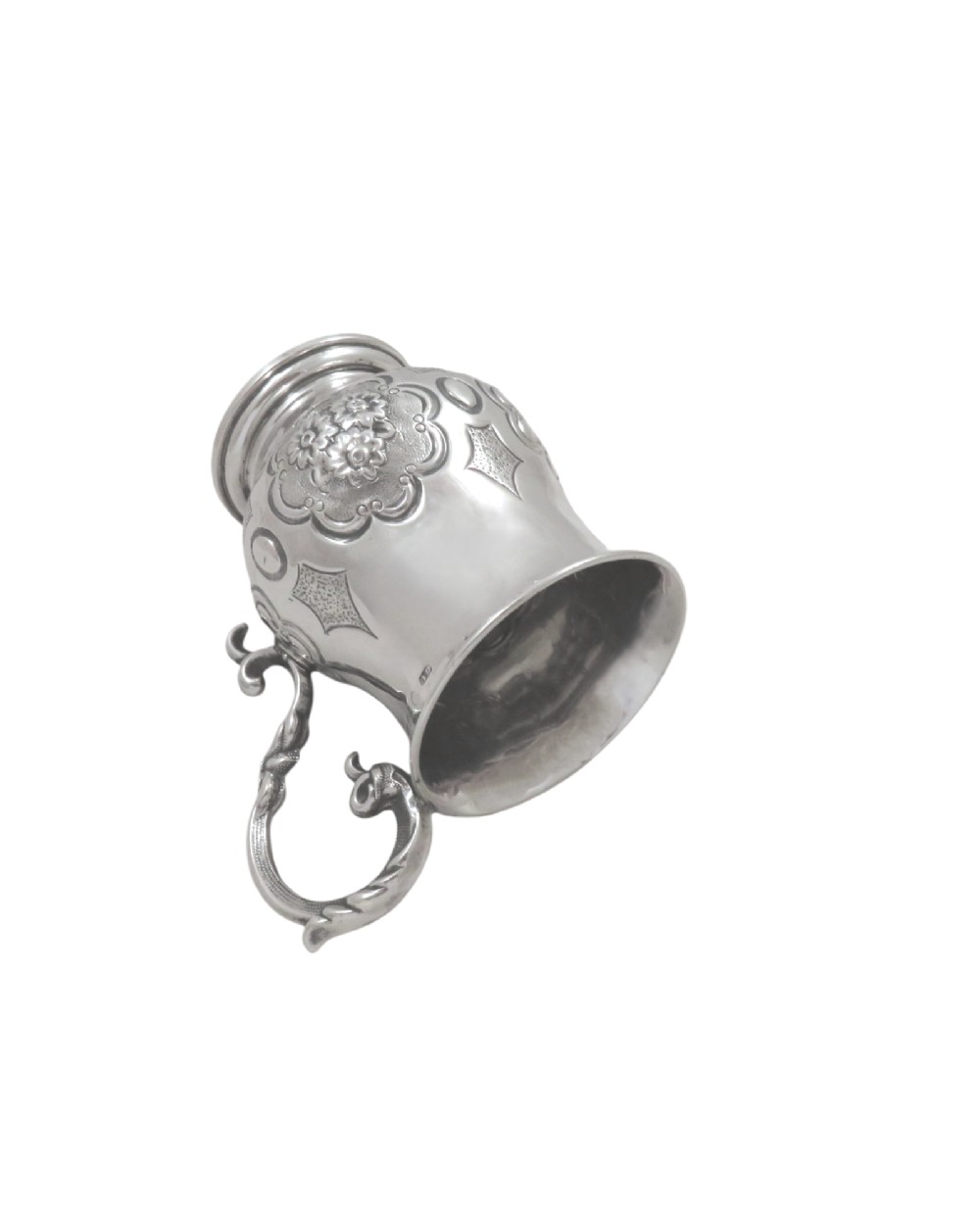 A Victorian sterling silver christening mug featuring floral chasing, geometric embossing, and a scroll handle. View IV