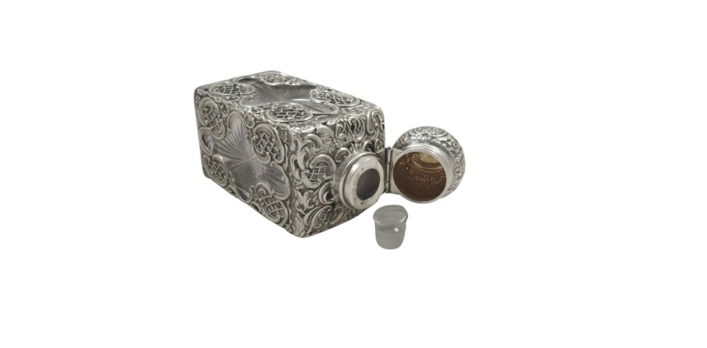 A late Victorian cut-glass scent bottle featuring an intricate pierced sterling silver outer scrollwork overlay and a silver embossed cap. View V