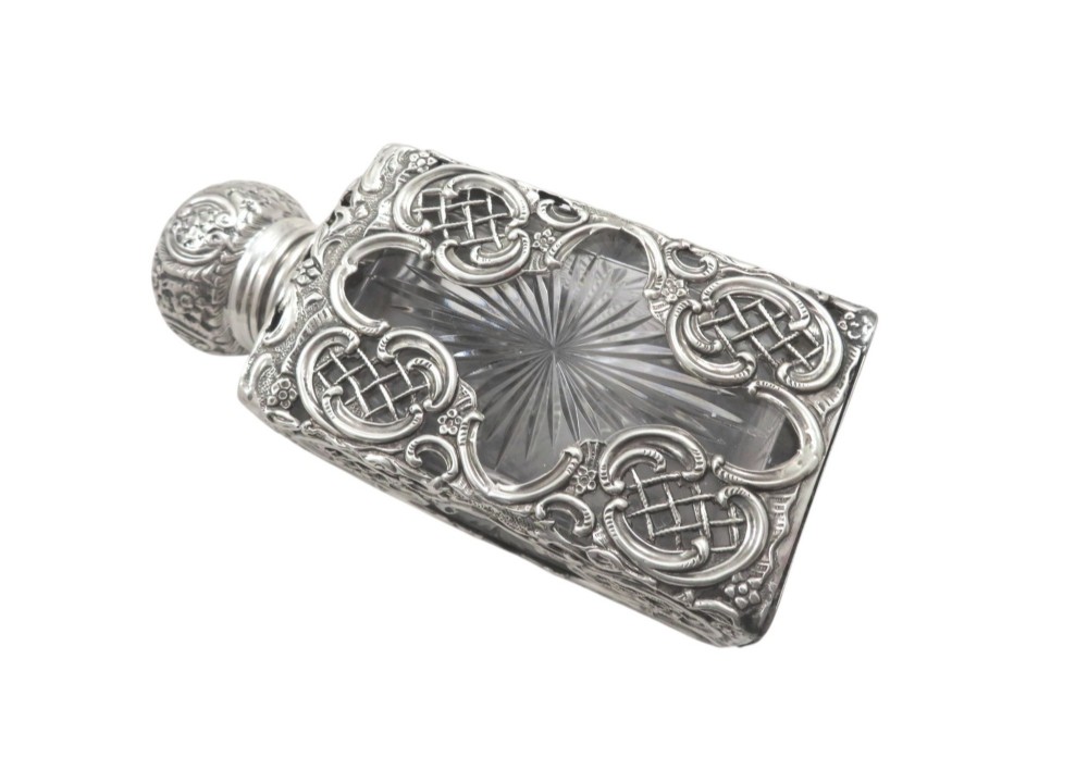 A late Victorian cut-glass scent bottle featuring an intricate pierced sterling silver outer scrollwork overlay and a silver embossed cap. View IX