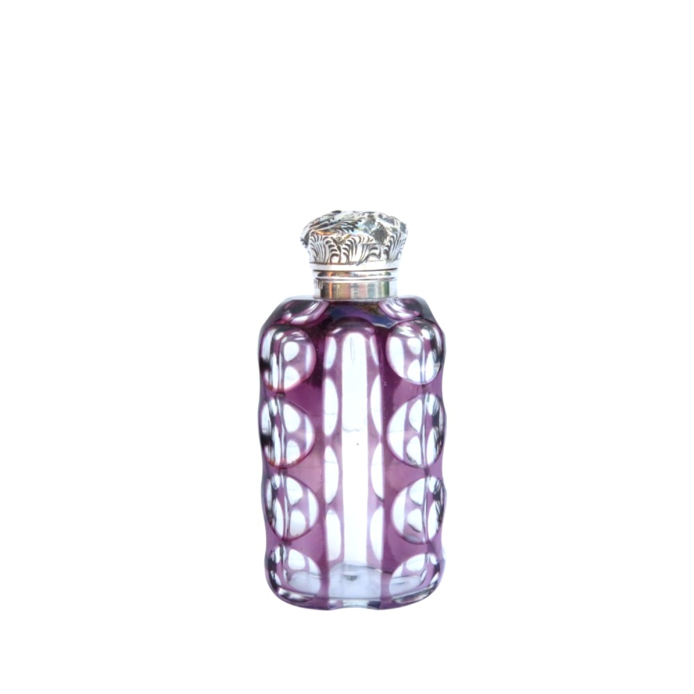 An Edwardian purple overlay cut glass scent bottle with oval clear cutouts and an embossed sterling silver cap.