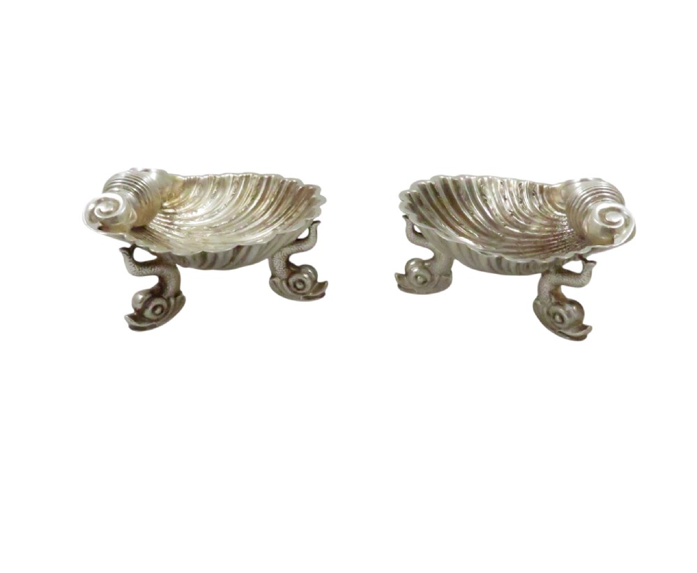 A pair of Victorian sterling silver open salt cellars shaped like scallop shells supported by cast dolphin feet. View V