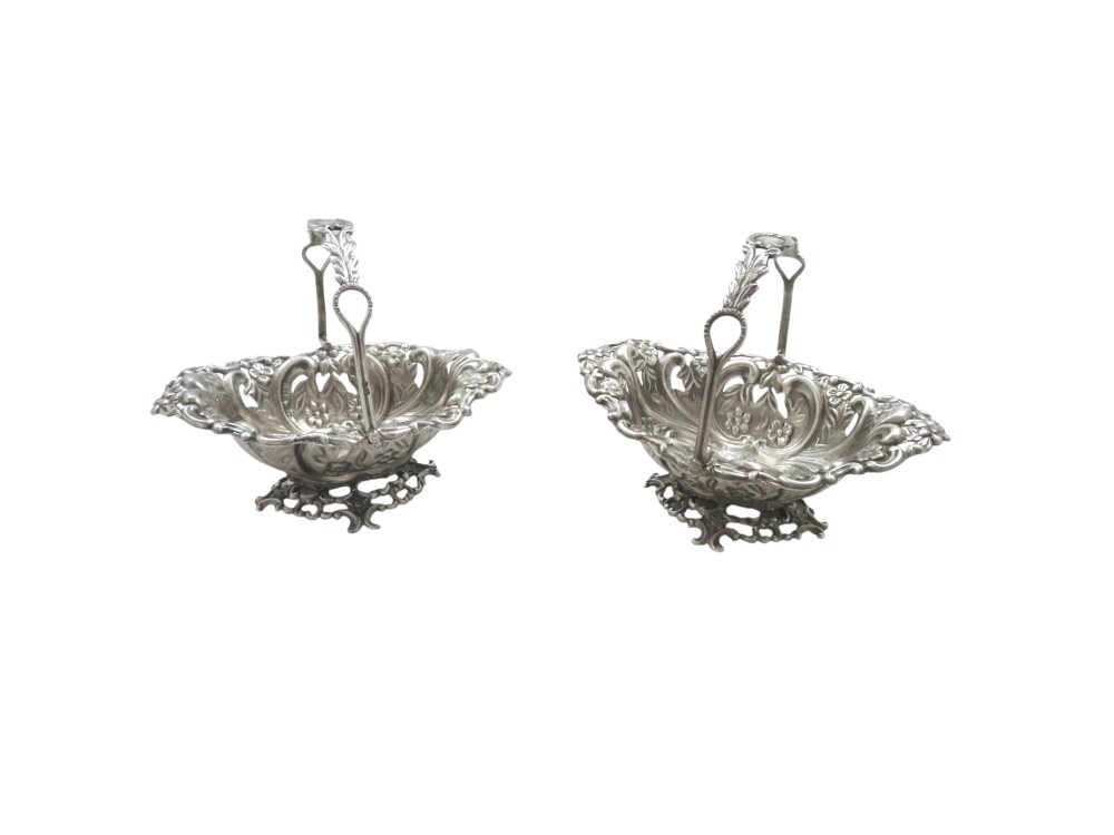 A pair of Edwardian sterling silver baskets featuring pierced floral openwork, swing handles, and scroll feet. View III