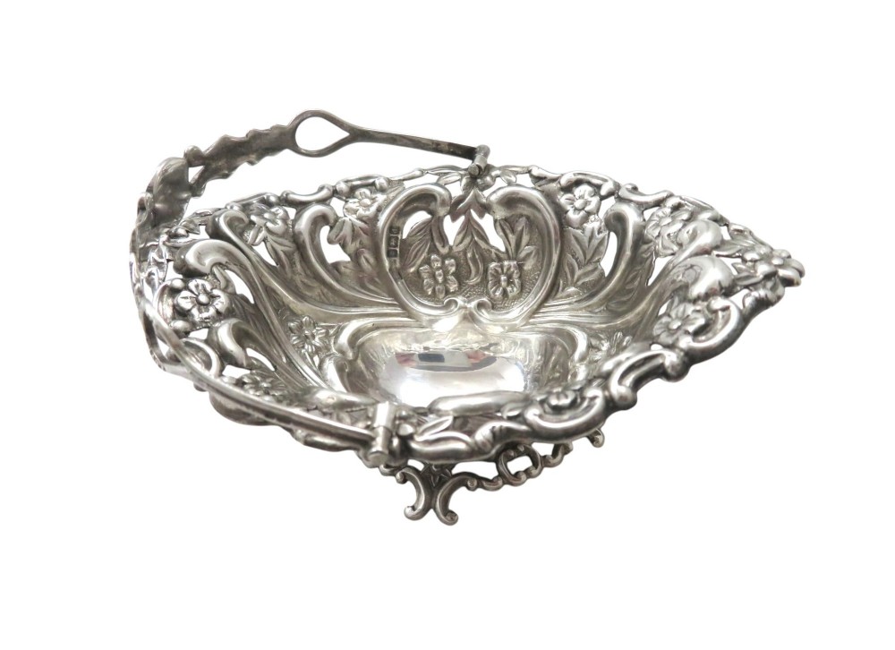 A pair of Edwardian sterling silver baskets featuring pierced floral openwork, swing handles, and scroll feet. View IV