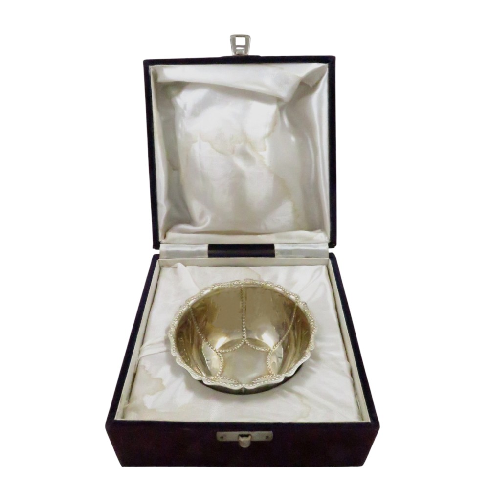 An Edwardian sterling silver fluted bowl featuring beaded rim detailing, resting inside a dark satin-lined presentation case.