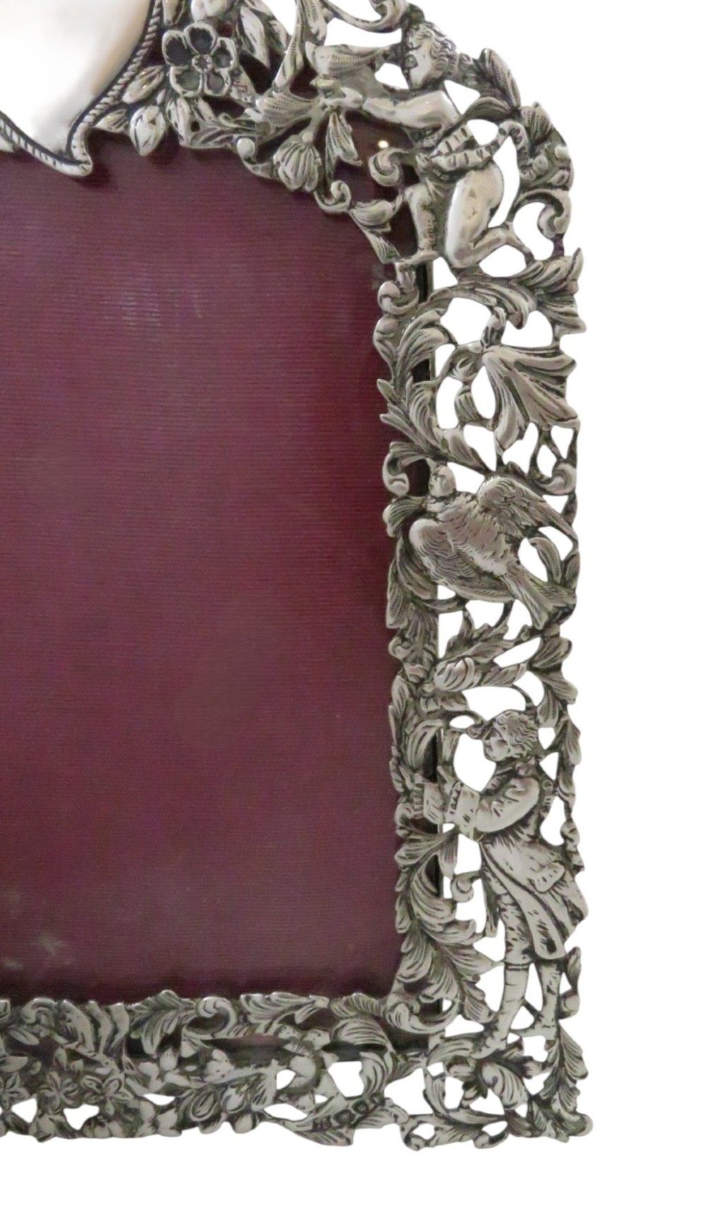 An ornate late Victorian sterling silver easel-back photo frame decorated with pierced cherubs, birds, and floral scrollwork, fitted with a burgundy velvet backing. View III