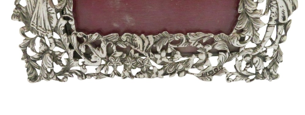 An ornate late Victorian sterling silver easel-back photo frame decorated with pierced cherubs, birds, and floral scrollwork, fitted with a burgundy velvet backing. View VIII