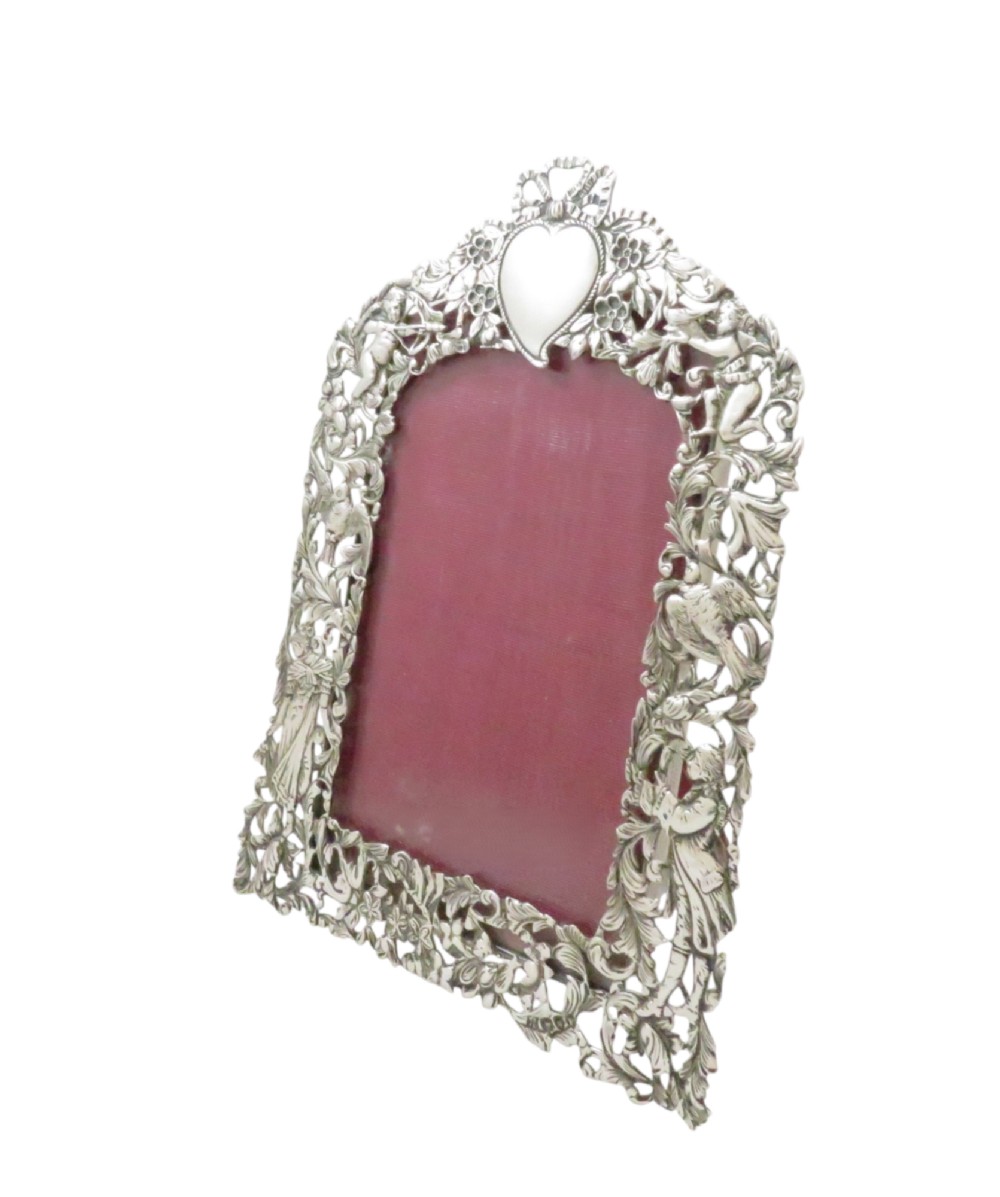 An ornate late Victorian sterling silver easel-back photo frame decorated with pierced cherubs, birds, and floral scrollwork, fitted with a burgundy velvet backing. View IX