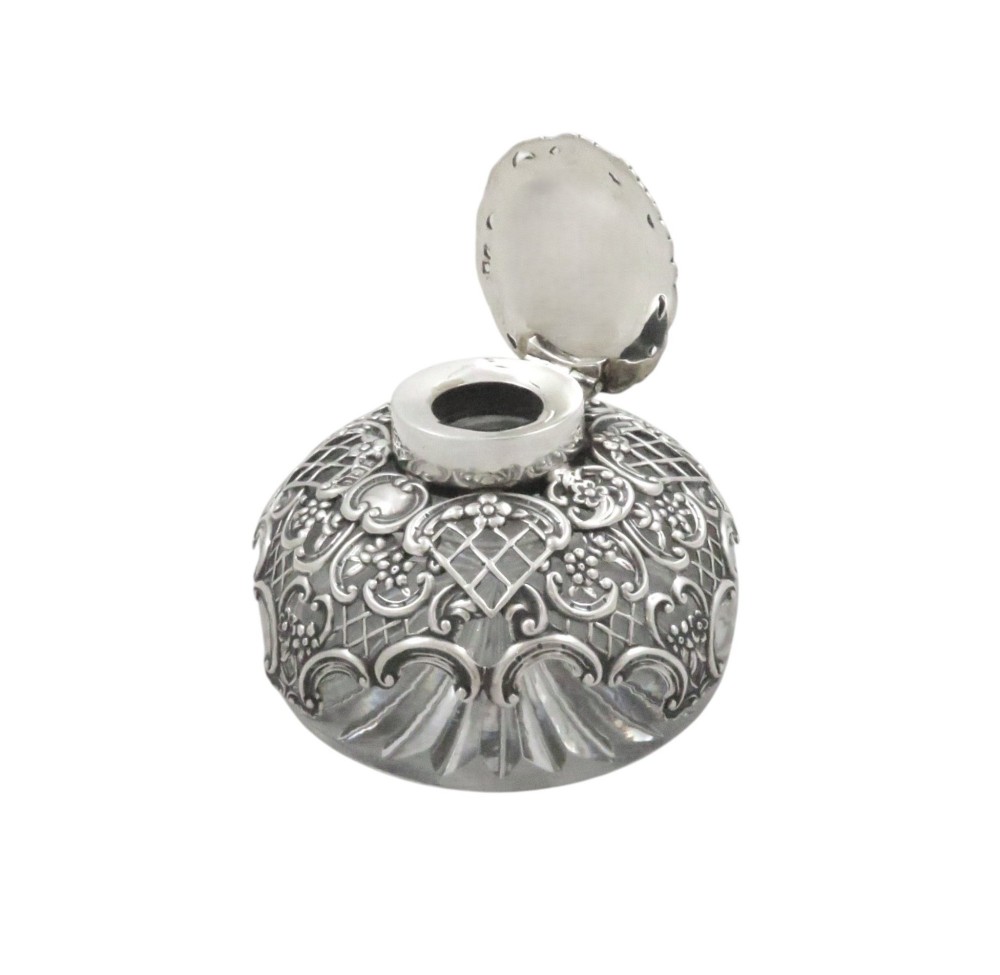 An antique Victorian clear cut-glass inkwell featuring an intricate repousse sterling silver collar and hinged lid. View III