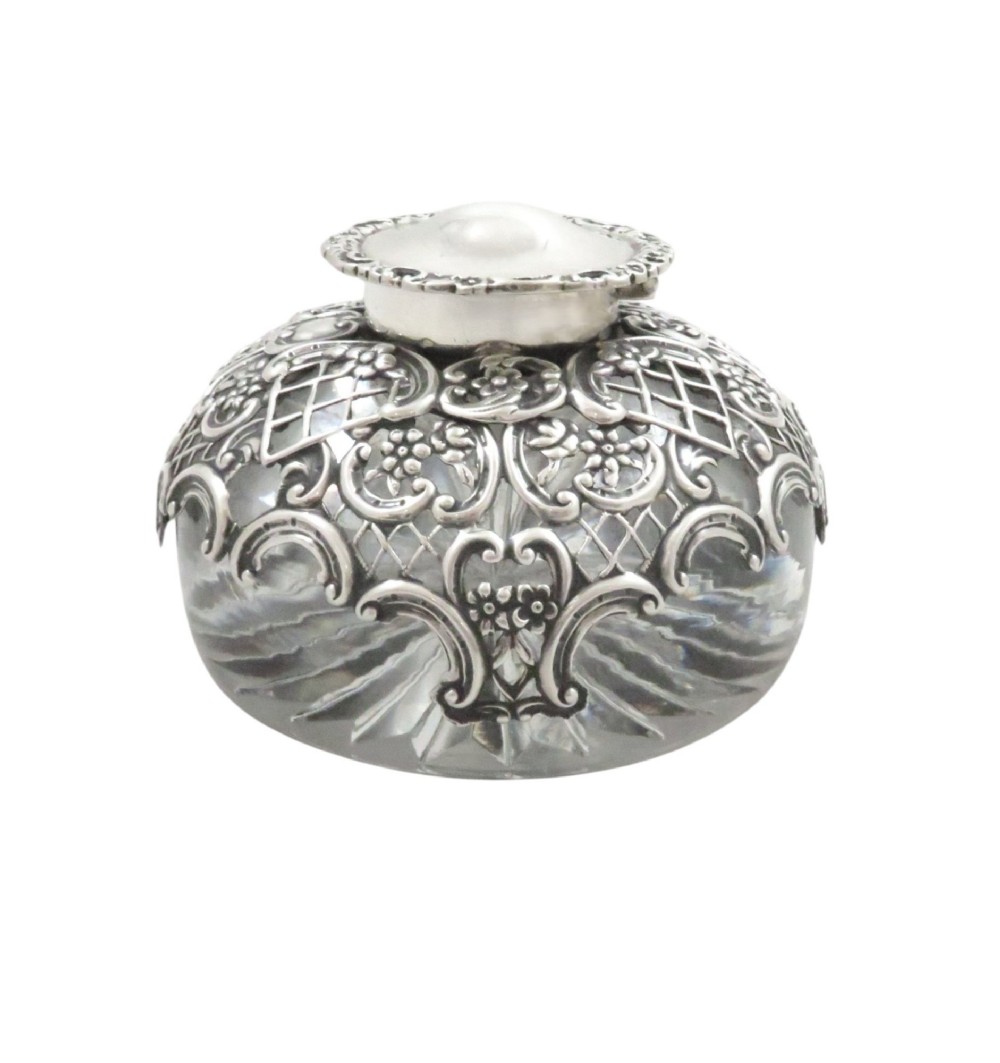 An antique Victorian clear cut-glass inkwell featuring an intricate repousse sterling silver collar and hinged lid. View V