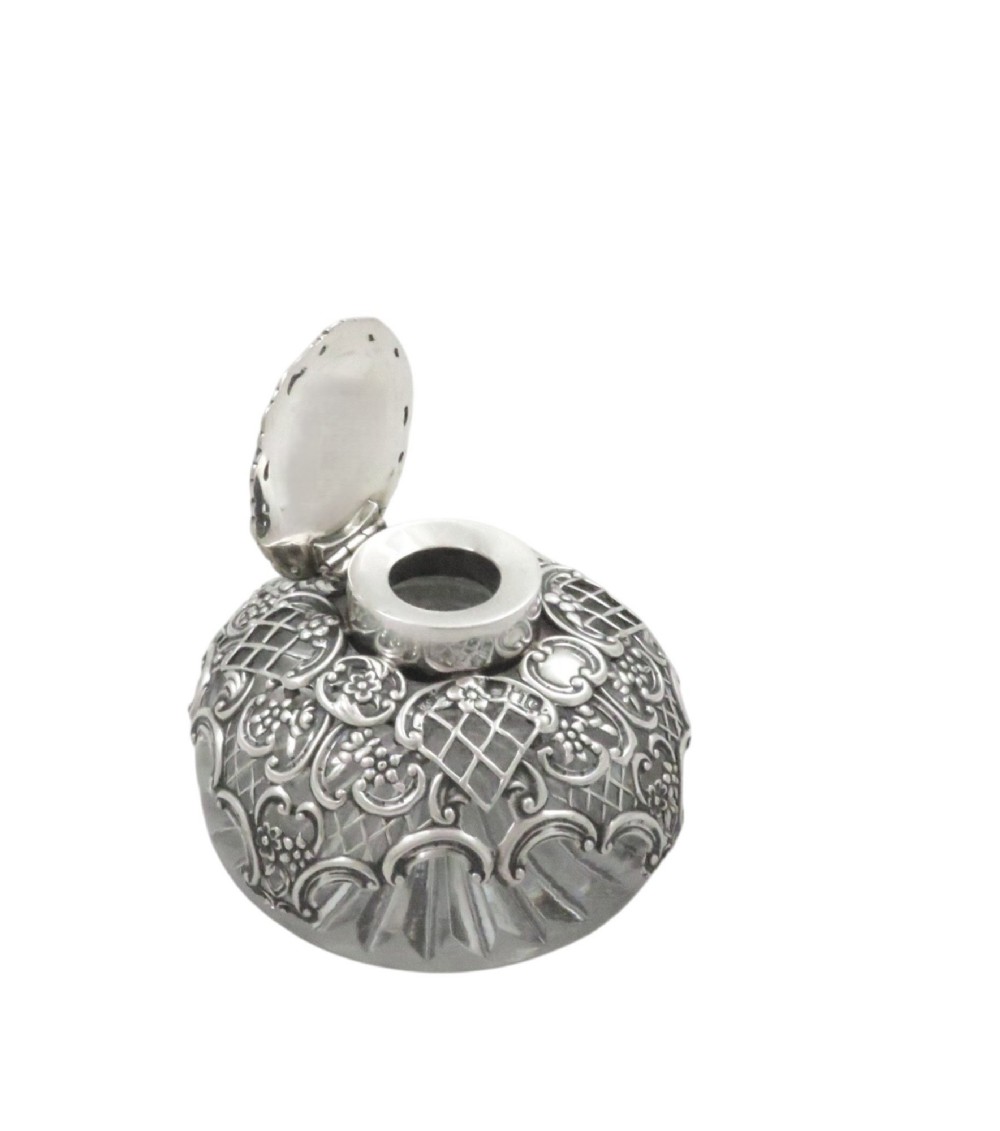 An antique Victorian clear cut-glass inkwell featuring an intricate repousse sterling silver collar and hinged lid. View VI