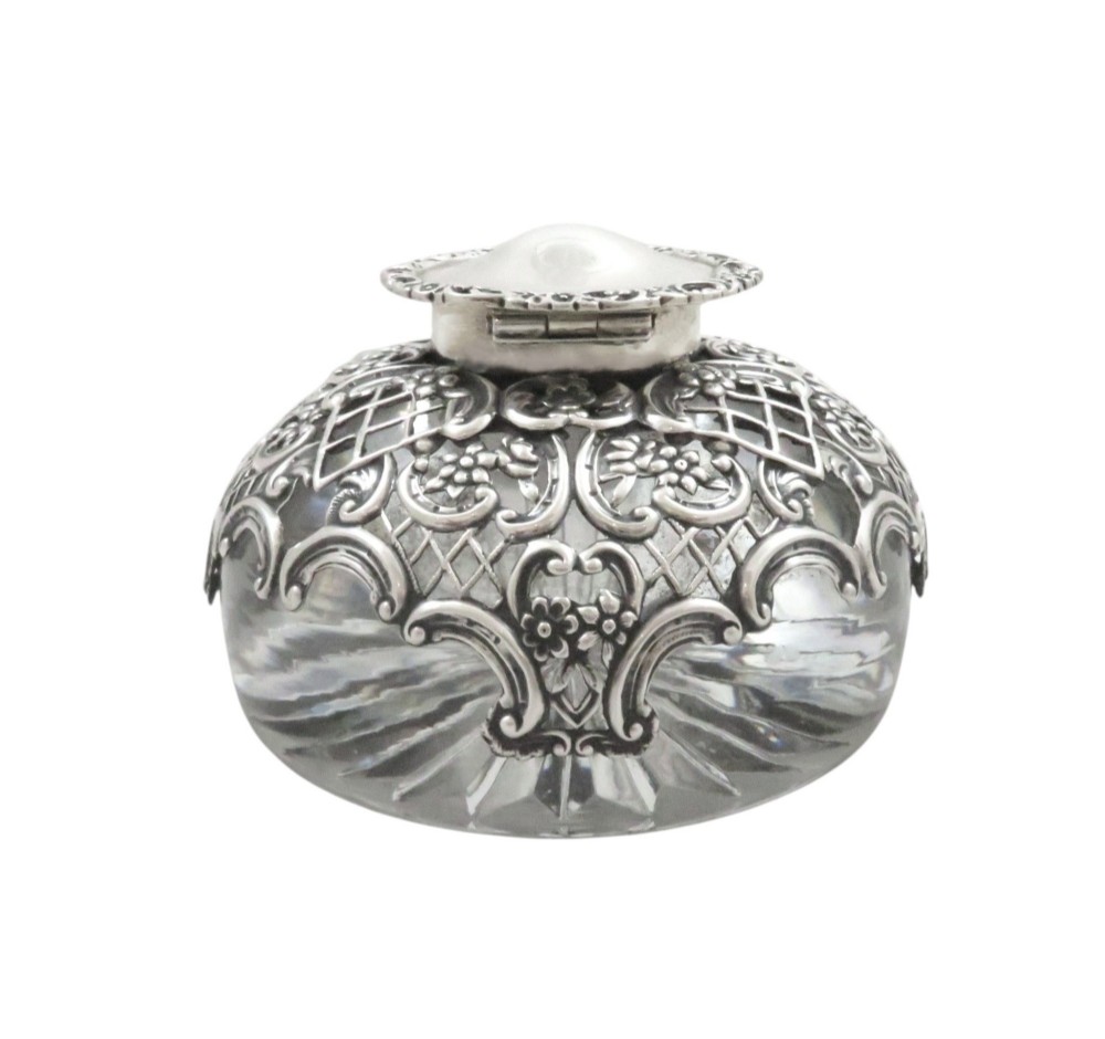 An antique Victorian clear cut-glass inkwell featuring an intricate repousse sterling silver collar and hinged lid. View VII