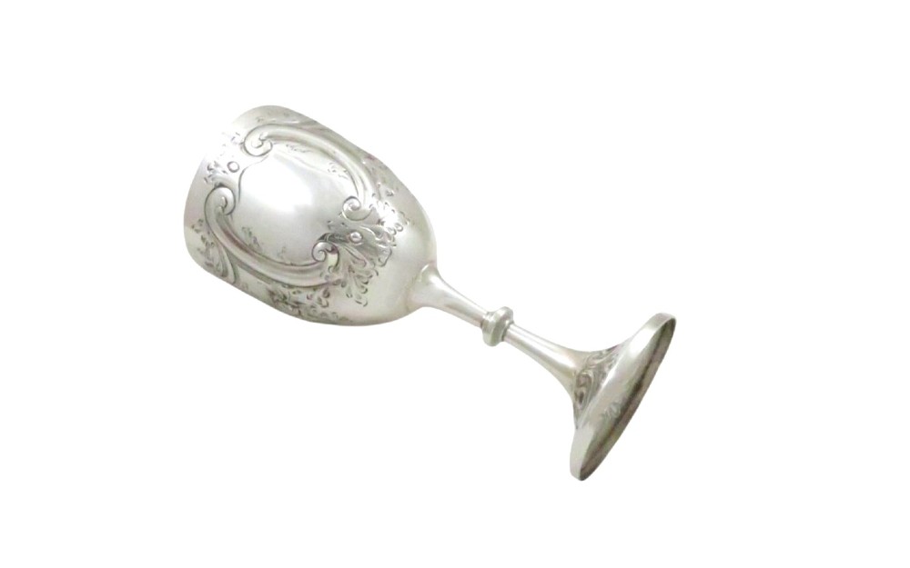 An Edwardian sterling silver wine goblet featuring scroll repousse engraving, an unengraved central cartouche, a knopped stem, and a gilt interior. View III