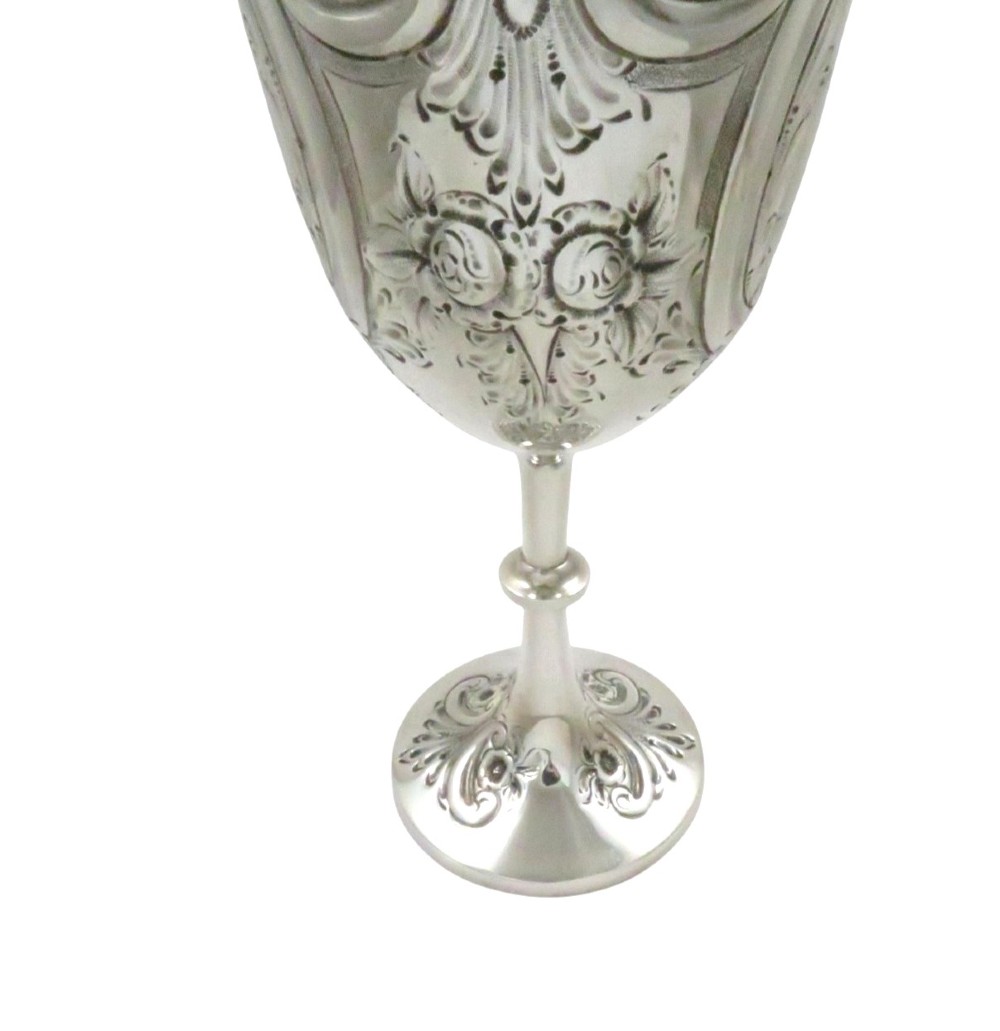 An Edwardian sterling silver wine goblet featuring scroll repousse engraving, an unengraved central cartouche, a knopped stem, and a gilt interior. View VI