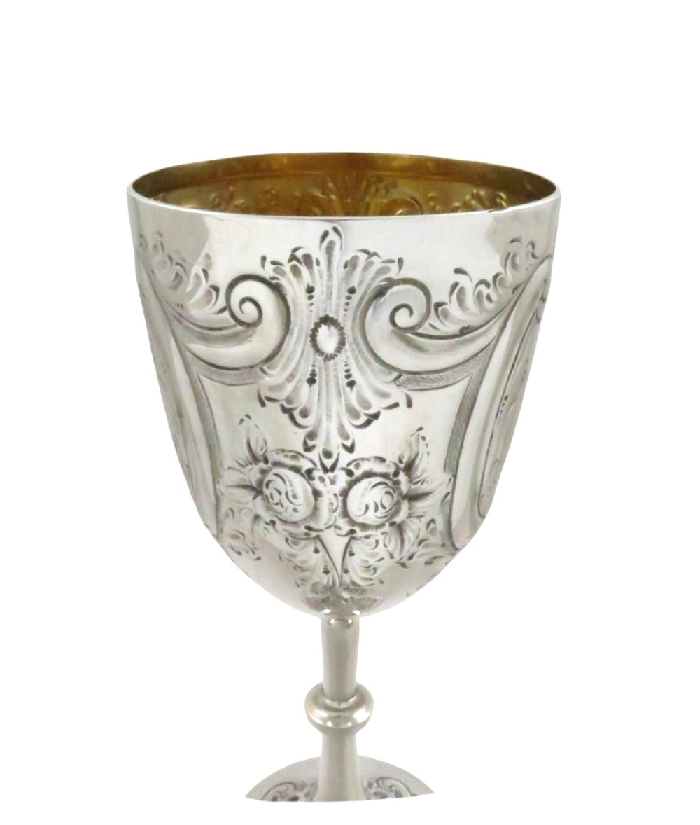 An Edwardian sterling silver wine goblet featuring scroll repousse engraving, an unengraved central cartouche, a knopped stem, and a gilt interior. View VIII