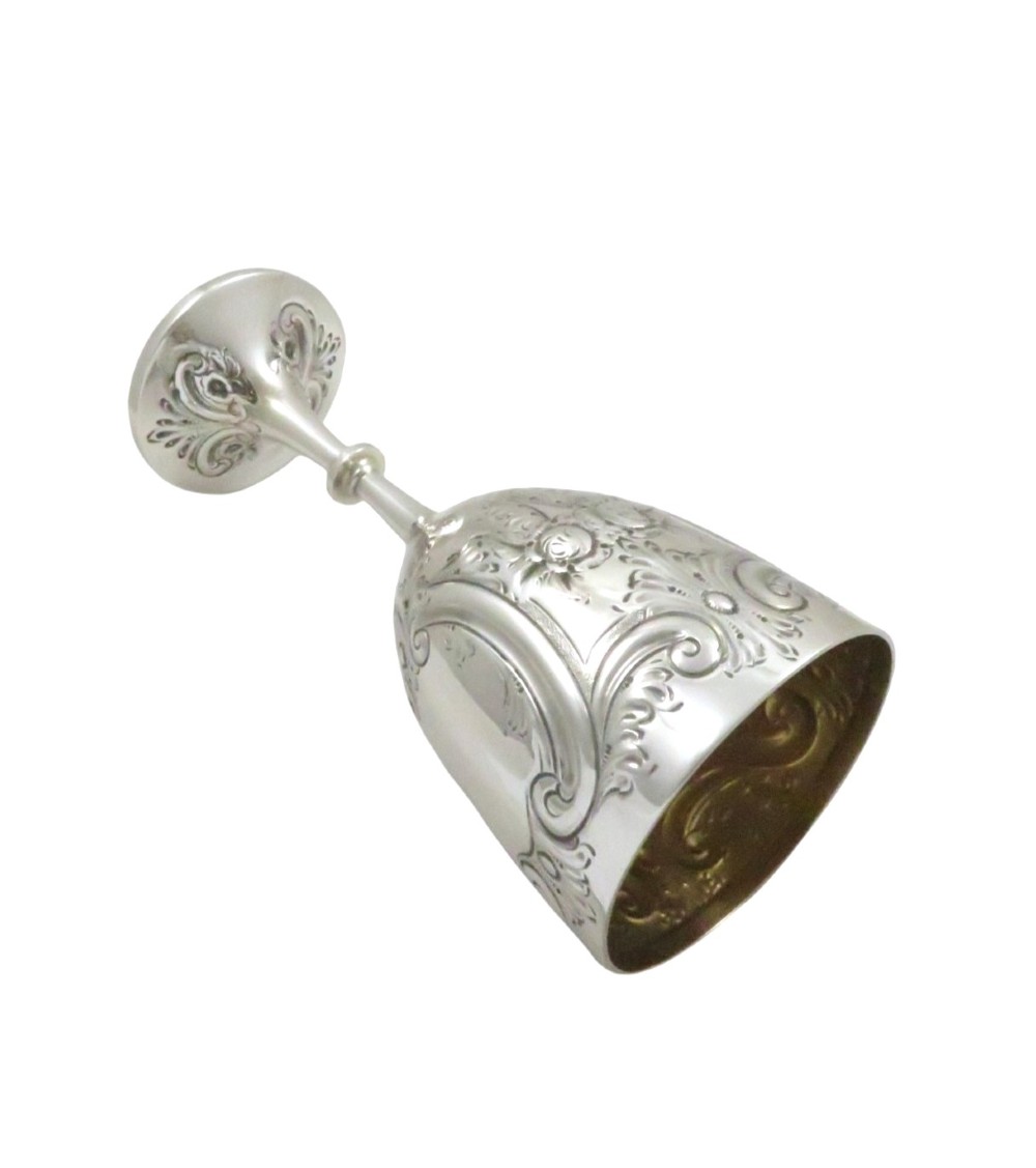 An Edwardian sterling silver wine goblet featuring scroll repousse engraving, an unengraved central cartouche, a knopped stem, and a gilt interior. View IX