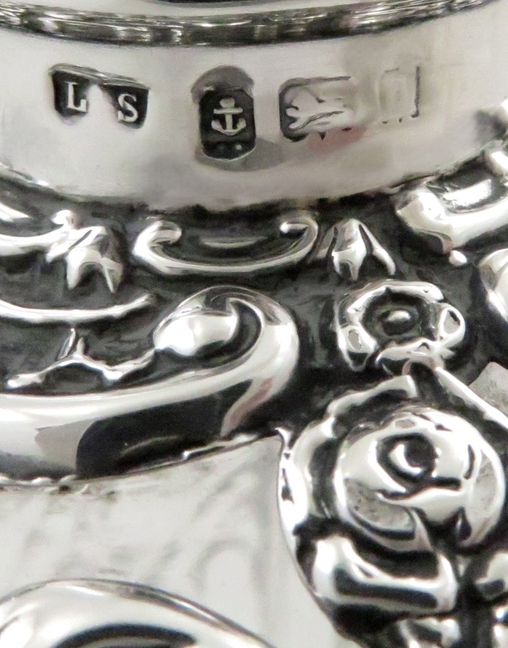An Edwardian clear glass scent bottle featuring a round body with ornate embossed sterling silver overlay and matching cap. View IV