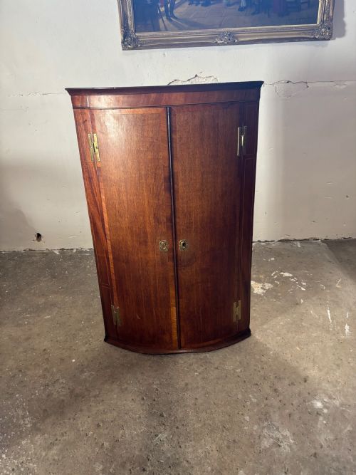 A GEORGIAN OAK AND MAHOGANY BOW FRONTED HANGING CORNER CUPBOARD