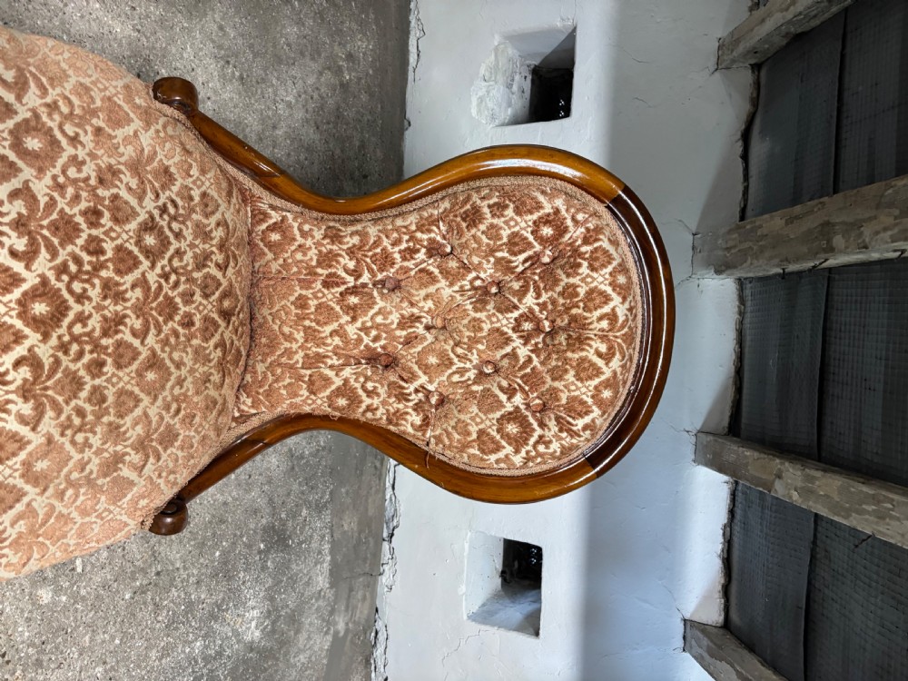 A Victorian mahogany ladies chair featuring a button-backed damask upholstered spoon frame and carved cabriole front legs. View II