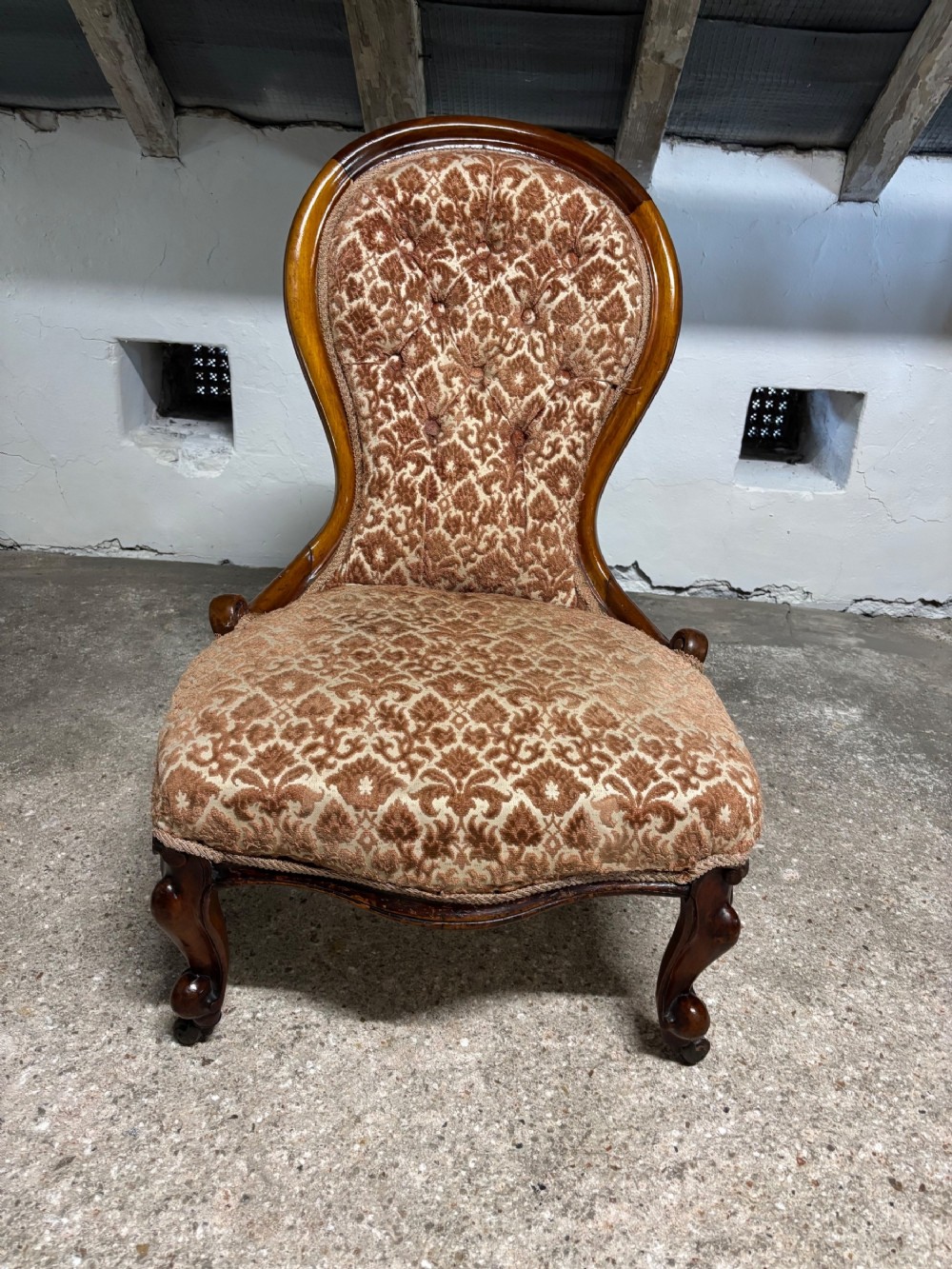 A Victorian mahogany ladies chair featuring a button-backed damask upholstered spoon frame and carved cabriole front legs.