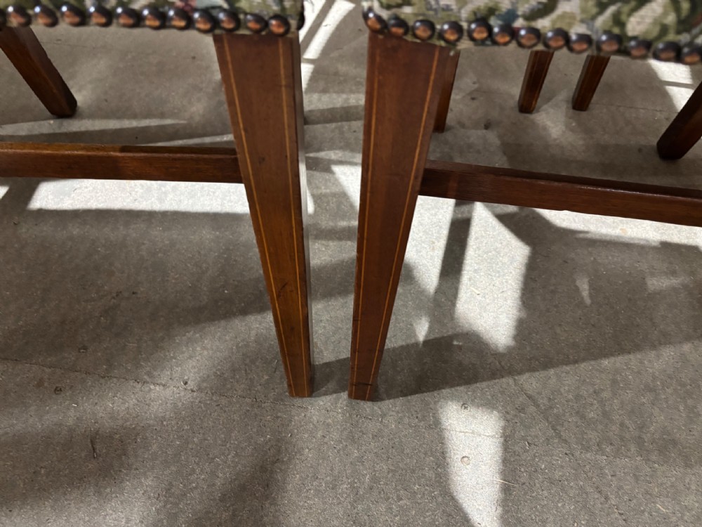 A set of seven George III mahogany dining chairs with curved top rails, vertical spindles, and floral tapestry upholstered seats. View VI