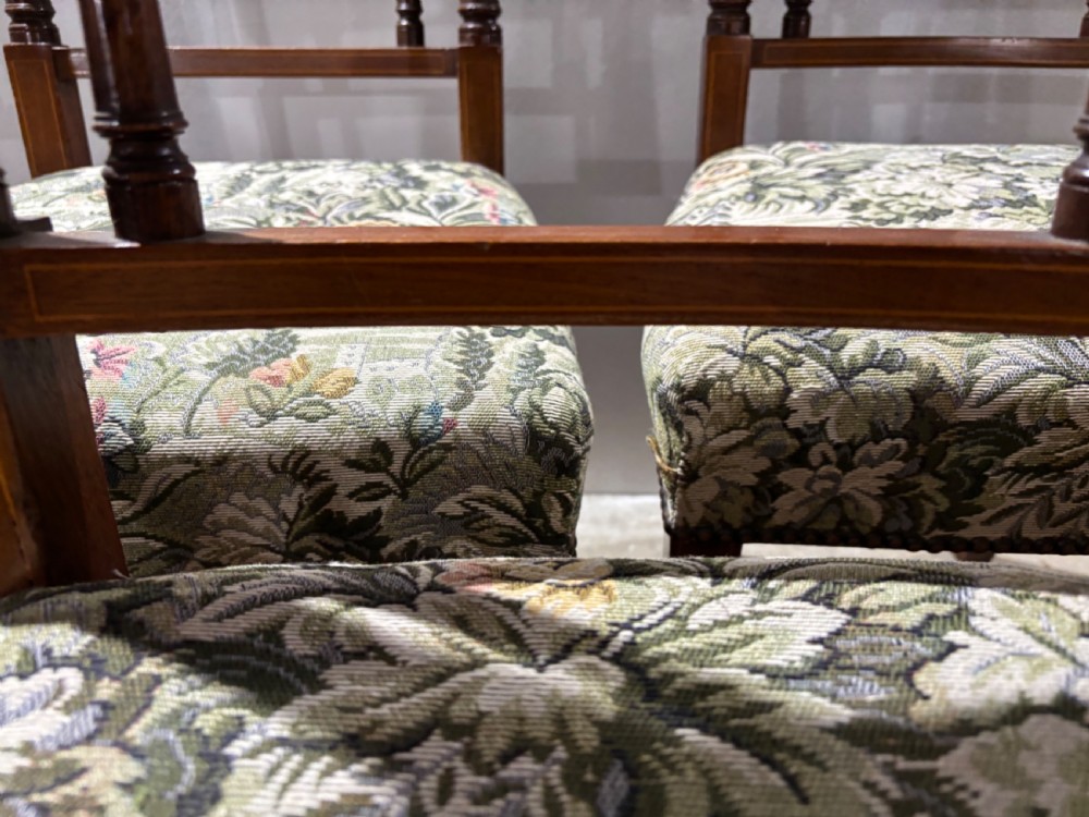 A set of seven George III mahogany dining chairs with curved top rails, vertical spindles, and floral tapestry upholstered seats. View VII