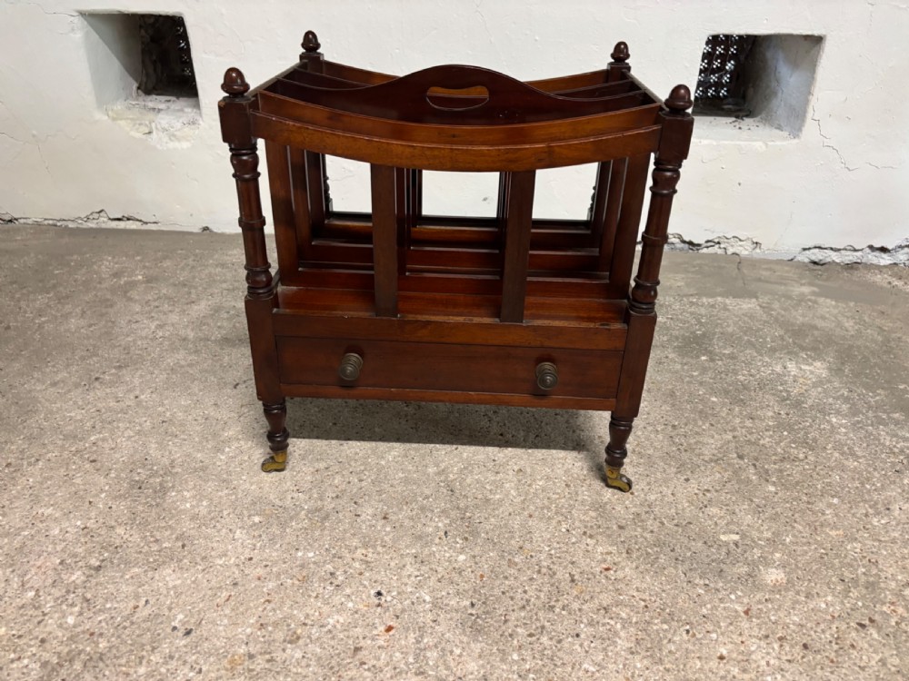 A Victorian mahogany Canterbury featuring slatted top compartments, turned corner posts with finials, a lower drawer, and brass castors. View III