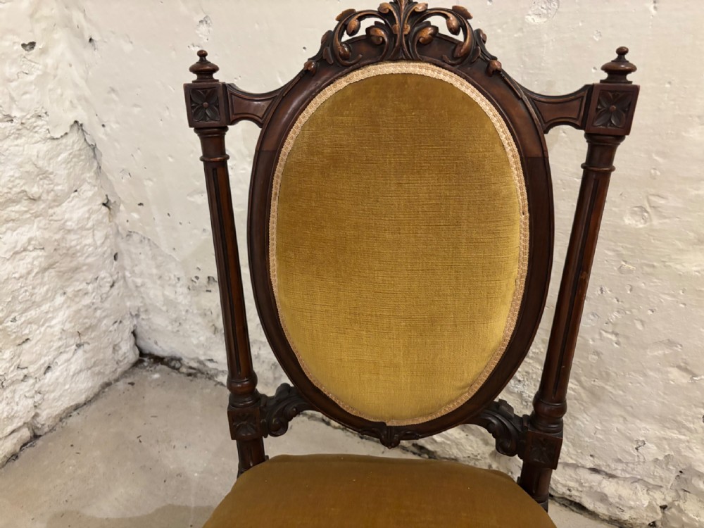Pair of late Victorian dark wood nursing chairs featuring one spindle-back chair with cream patterned fabric and one oval-back chair upholstered in mustard yellow velvet. View IV