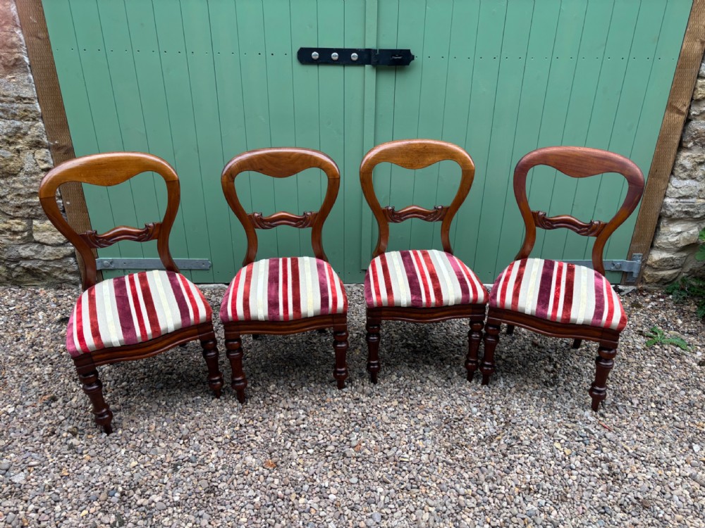 A set of four Victorian mahogany dining chairs with curved balloon backs, carved mid-rails, striped red velvet seats, and turned front legs. View V